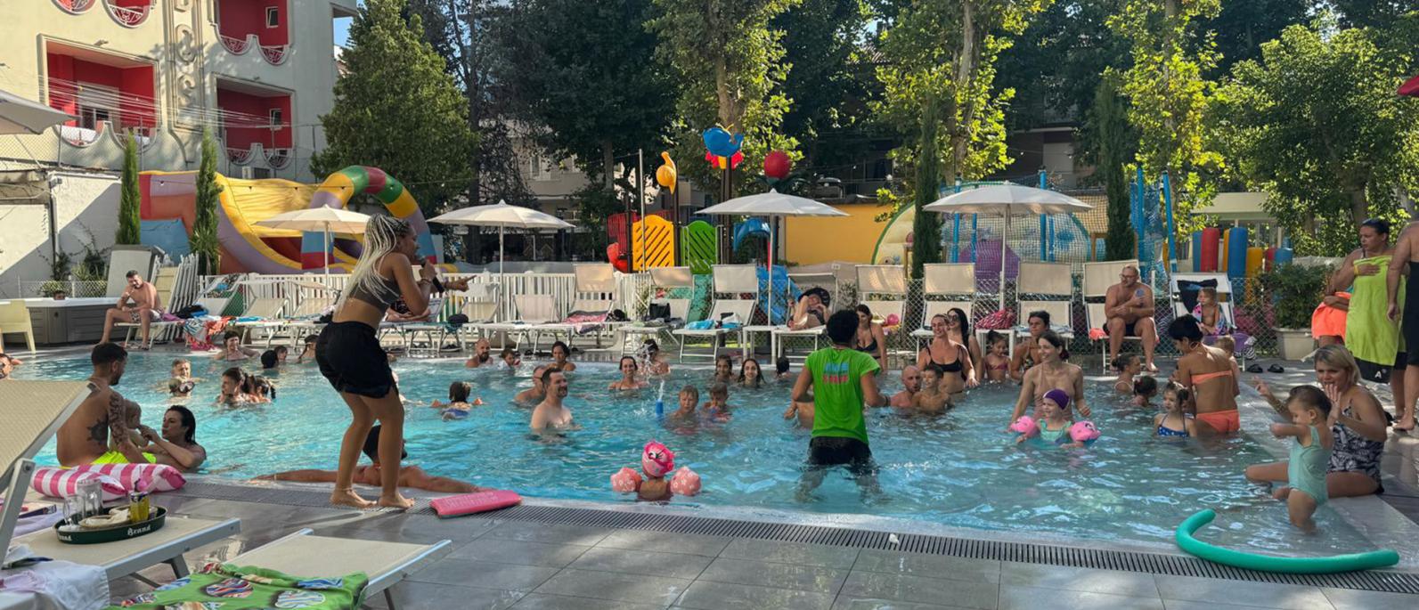 Piscina affollata con famiglie e bambini che si divertono.